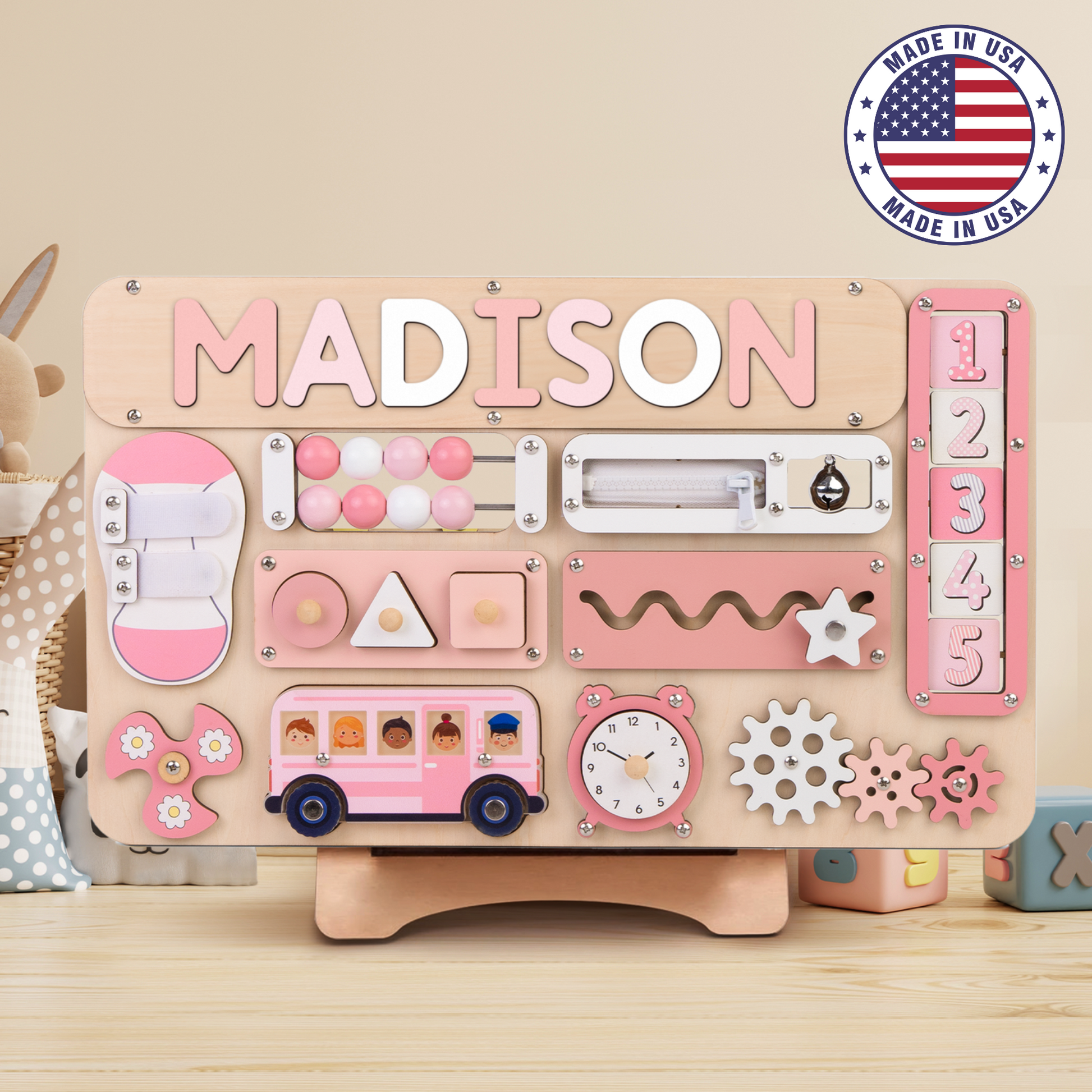 A personalized Montessori busy board for toddlers, featuring rotating numbers and various sensory activities, with the name 'Madison' printed on it.